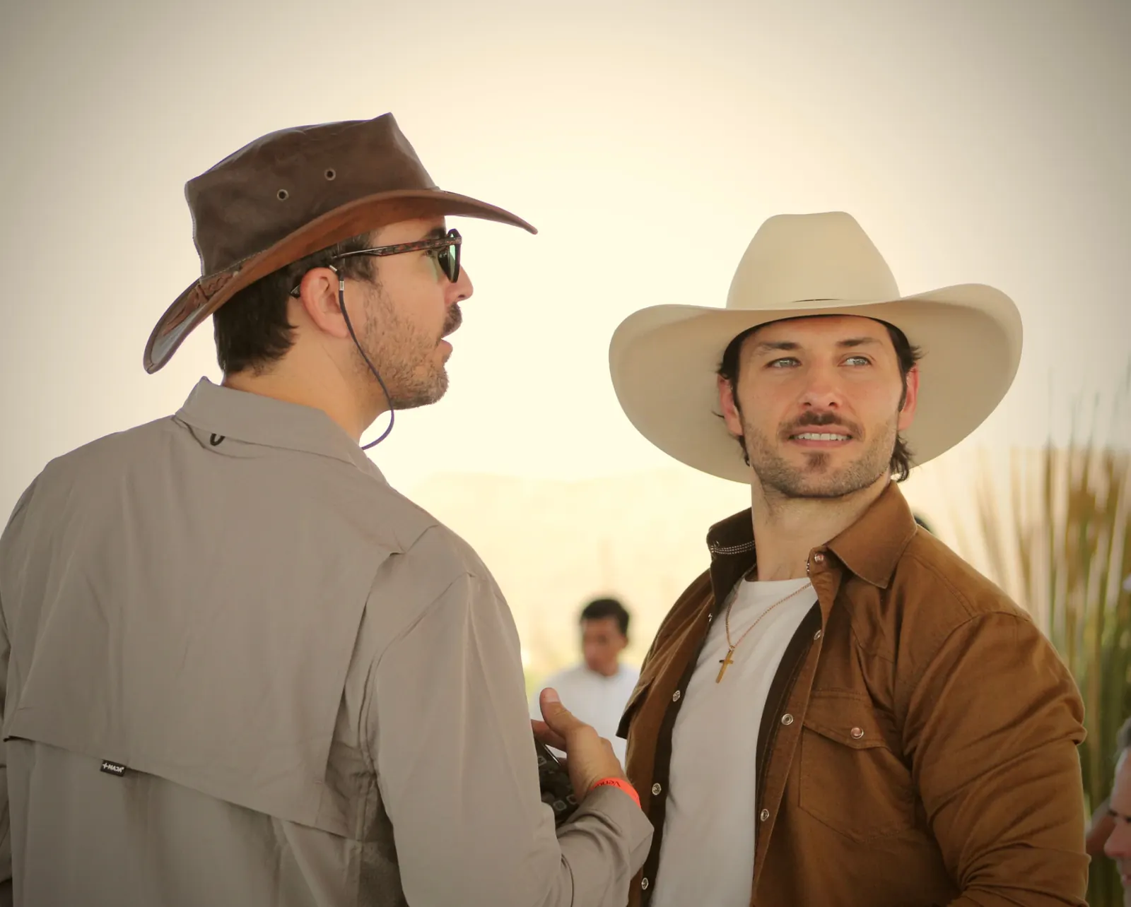 Dos hombres con sombrero western conversando durante el festival del vino