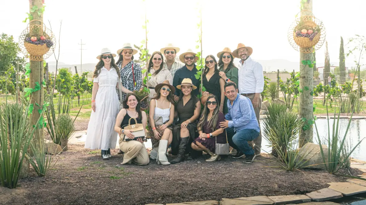 Foto grupal de asistentes con canastas de uva en el viñedo de Sierto
